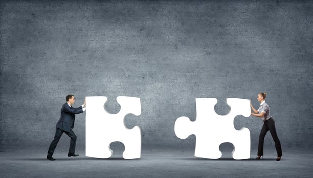 Team of business people collaborate holding up jigsaw puzzle pieces as a solution to a problem.jpeg