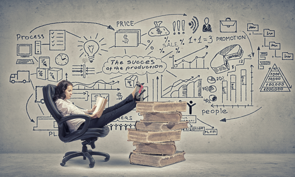 Young businesswoman sitting in chair with her legs on pile of books