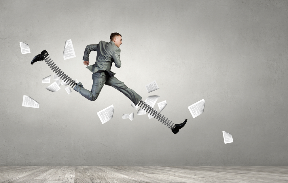 Businessman in suit jumping with big springs on feet