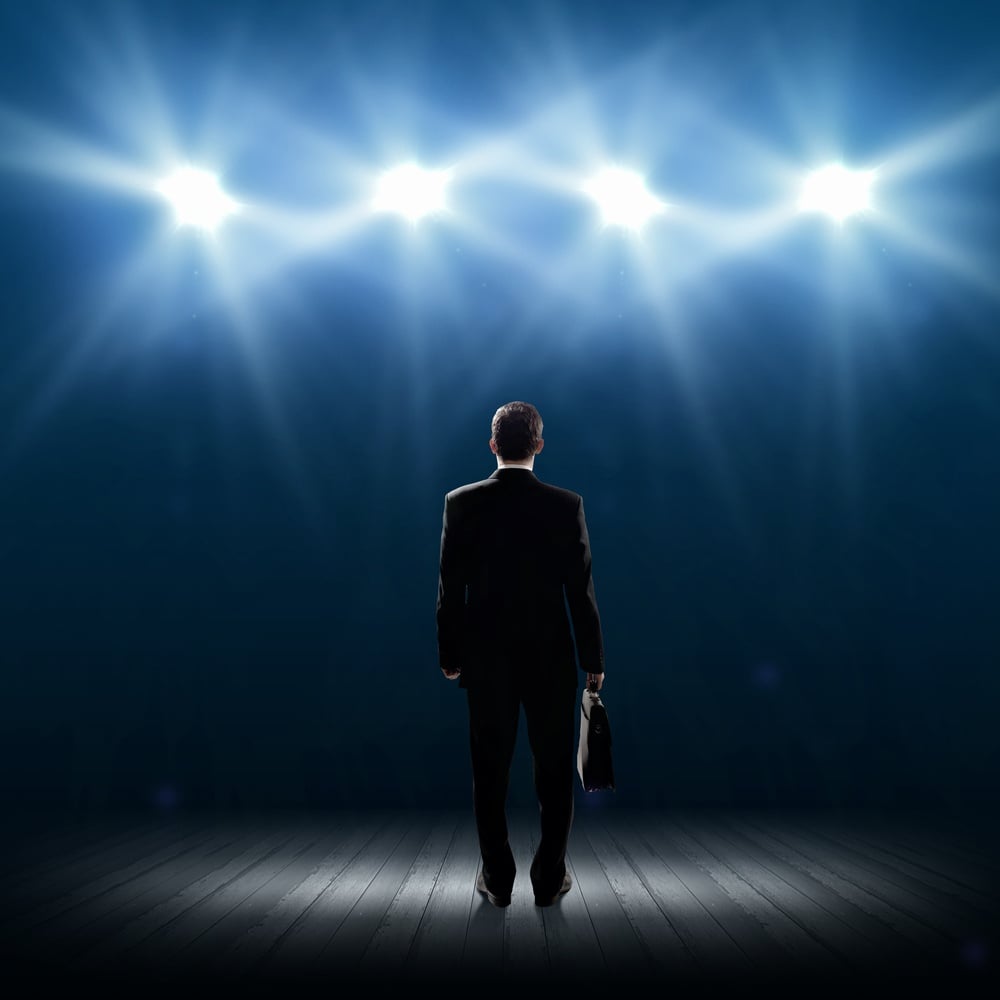 Rear view of businessman standing in lights of stage.jpeg